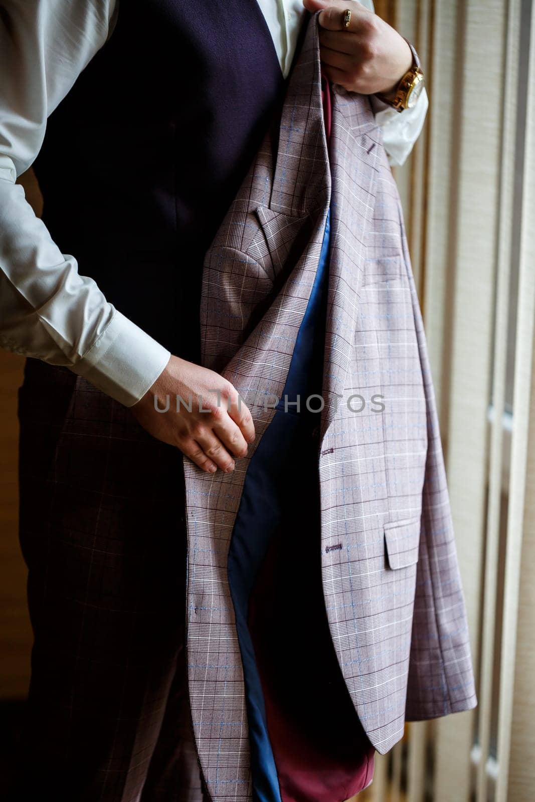 Man puts on a wedding suit and accessories on the wedding day.