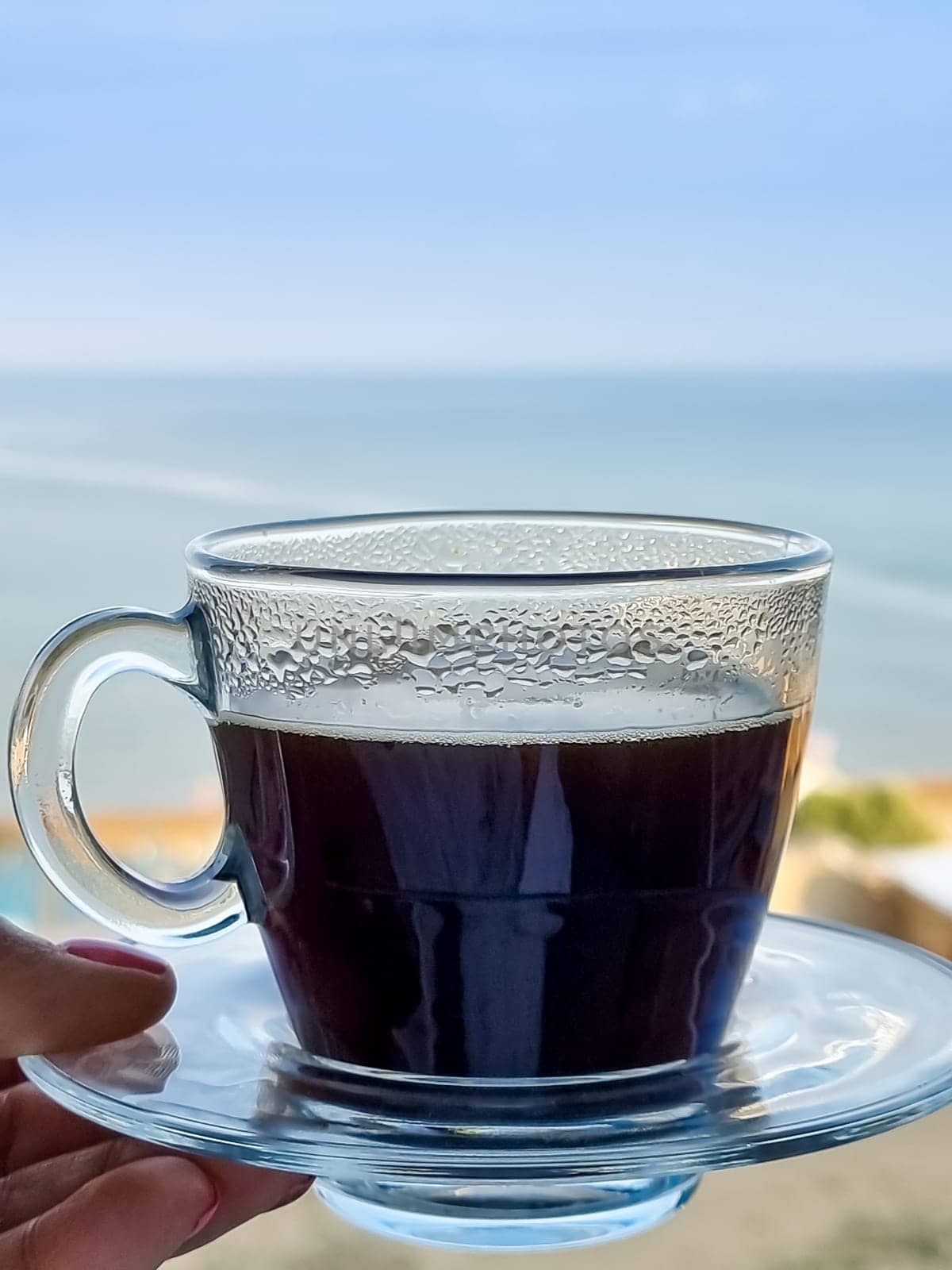 White coffee mug in man hand on terrace overlooking sea or ocean. Enjoying morning coffee on paradise island