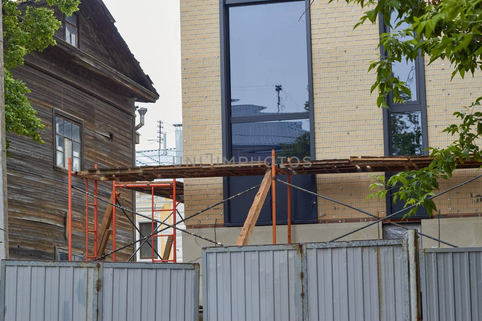 Photo of scaffolding and facades of buildings with fence. Construction and repair.