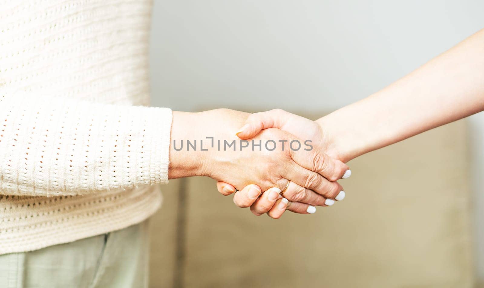 Doctor shaking hands with a senior patient at home. Nurse handschaking with an old lady. Close up of a helping hand.