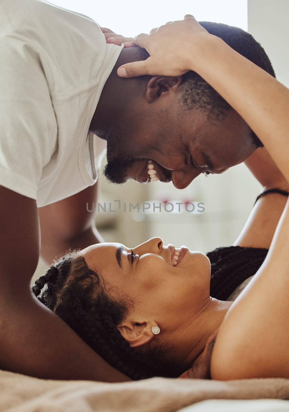Black couple, love and home bedroom romance while happy and intimate together on bed at home, apartment or hotel. Face of young man and woman in happy marriage with commitment and care on honeymoon by YuriArcurs