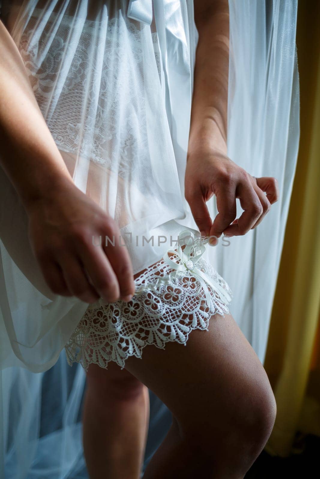 bride puts on a beautiful garter on her leg