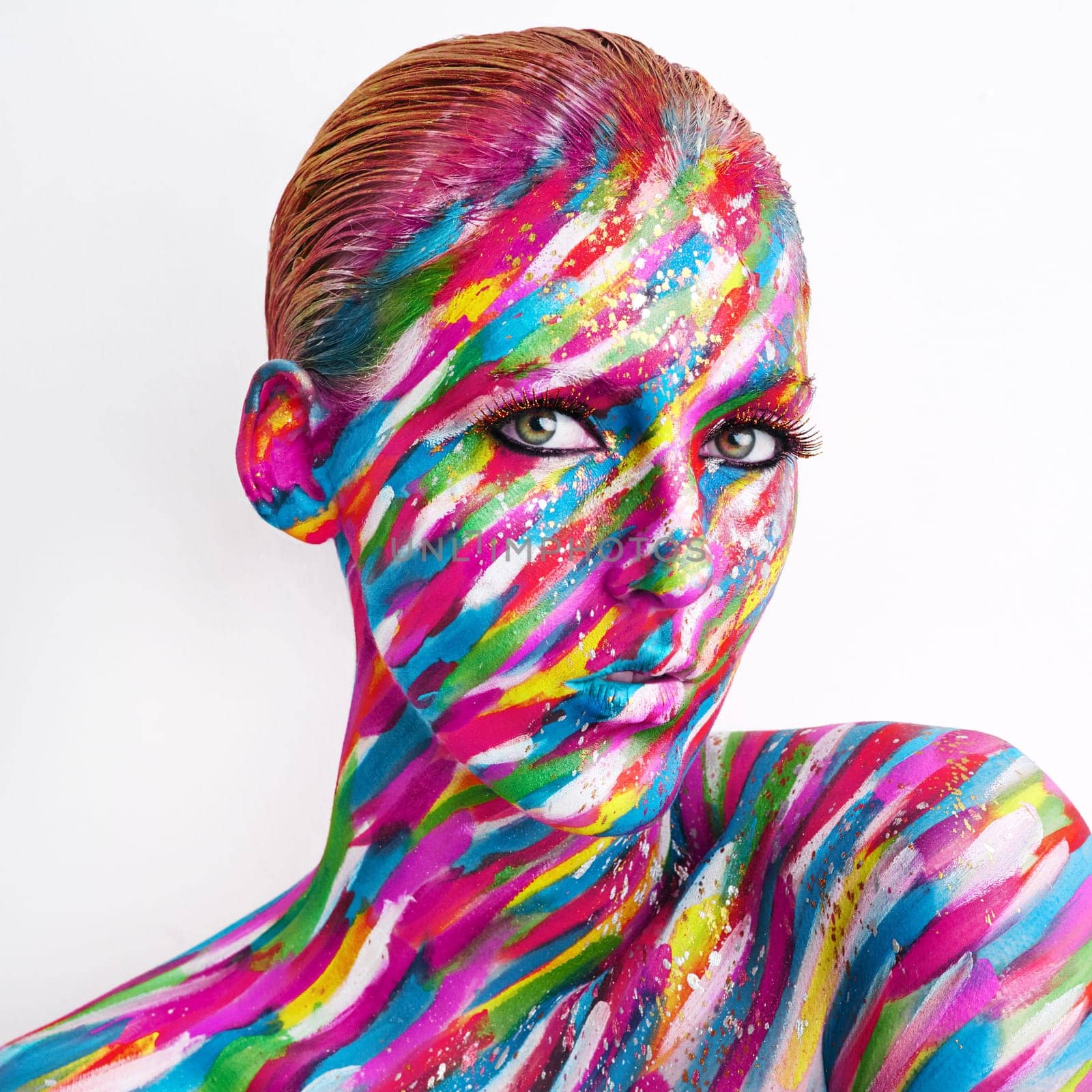 Studio shot of a young woman posing with brightly colored paint on her face against a white background.