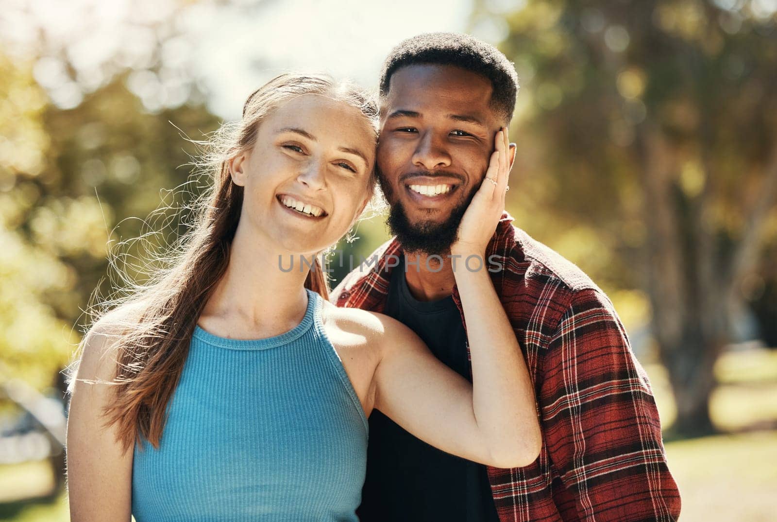 Portrait of interracial couple, young people and relax in park, sunshine and summer for love, care or quality time together. Happy man, smile woman and diversity date in nature, outdoor and happiness.