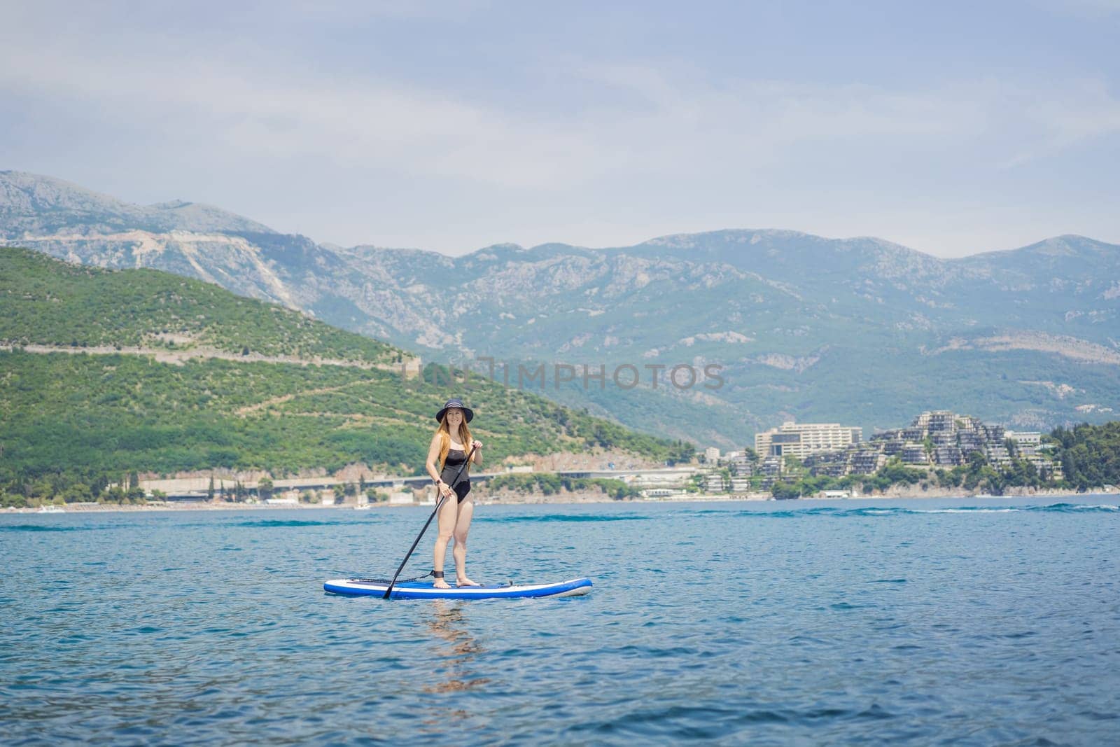 Young women Having Fun Stand Up Paddling in blue water sea in Montenegro. Against the backdrop of the Montenegrin mountains. SUP by galitskaya