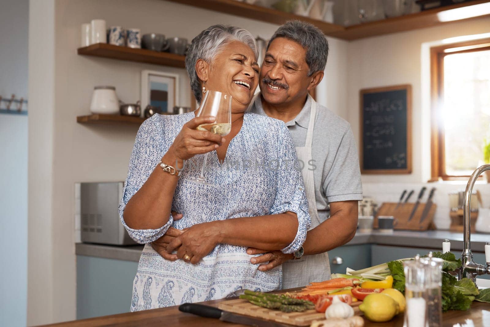 Hug, old woman and man in kitchen with wine glass, happiness and cooking healthy vegetable dinner together. Smile, love and food, happy senior couple in retirement with drink, vegetables and wellness.