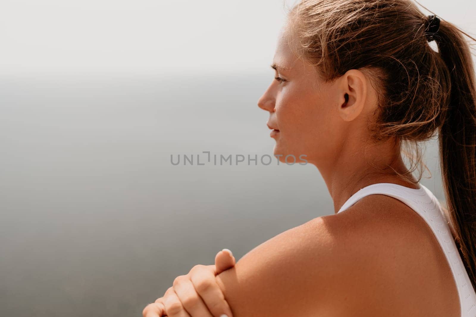 Middle aged well looking woman with black hair doing Pilates with the ring on the yoga mat near the sea on the pebble beach. Female fitness yoga concept. Healthy lifestyle, harmony and meditation.