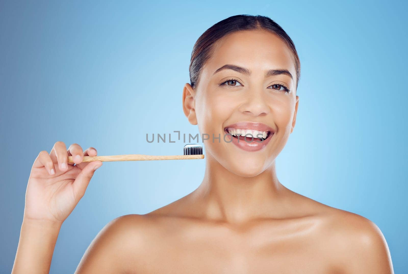 Brushing teeth, woman and portrait of bamboo toothbrush for dental healthcare, breath and cleaning cosmetics. Happy female, eco wooden brush and toothpaste for mouth, smile and studio blue background by YuriArcurs