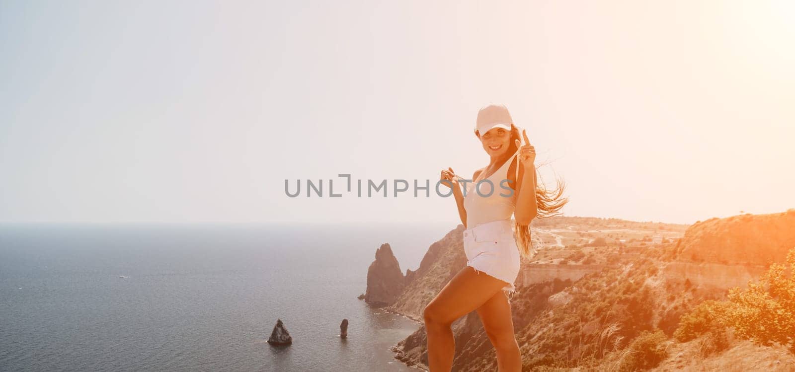 Woman travel sea. Young Happy woman in a long red dress posing on a beach near the sea on background of volcanic rocks, like in Iceland, sharing travel adventure journey