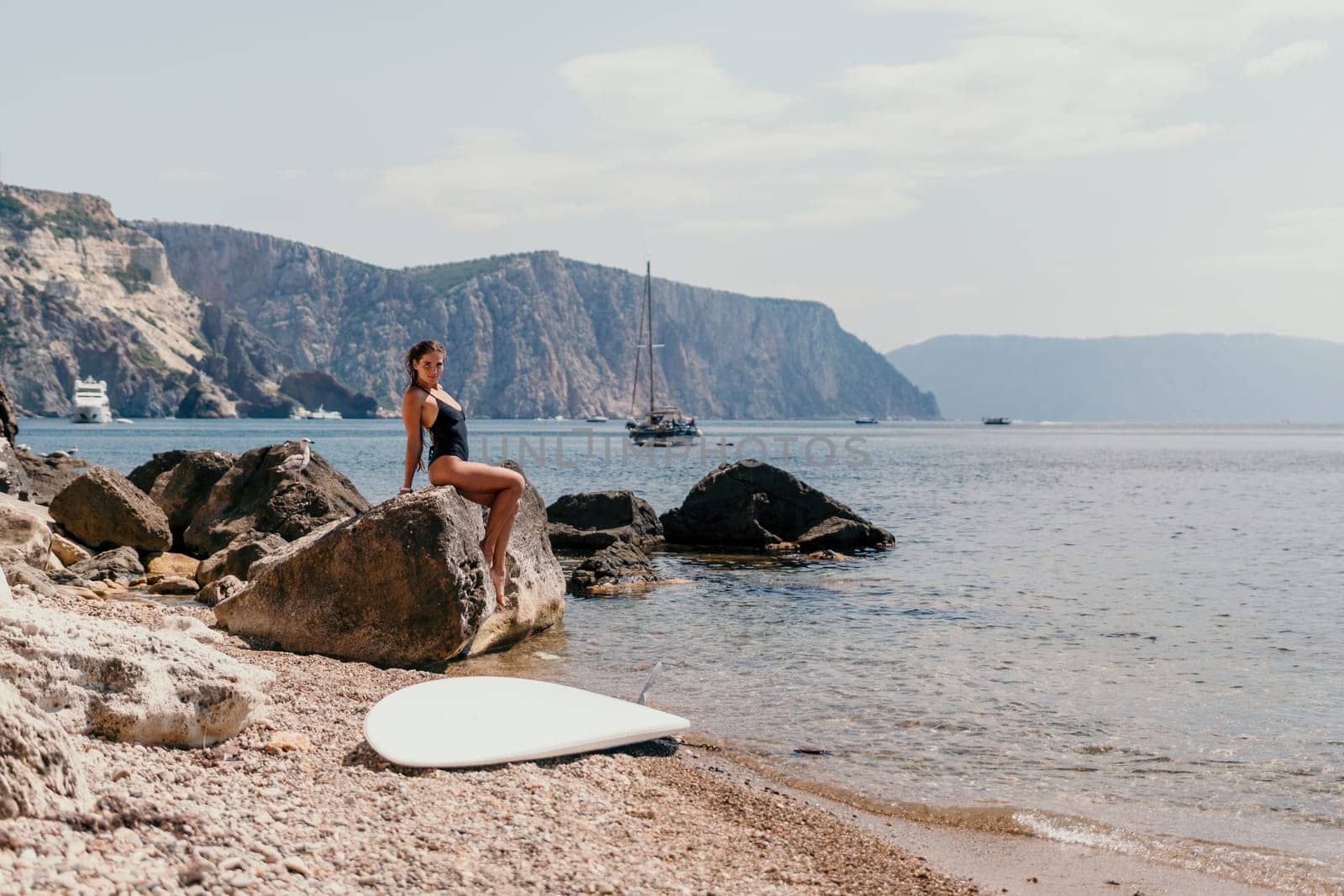 Woman travel sea. Young Happy woman in a long red dress posing on a beach near the sea on background of volcanic rocks, like in Iceland, sharing travel adventure journey