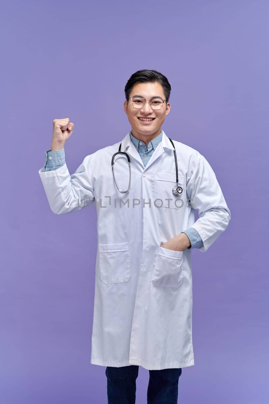Young handsome man wearing doctor uniform and stethoscope pointing thumb up to the side 
