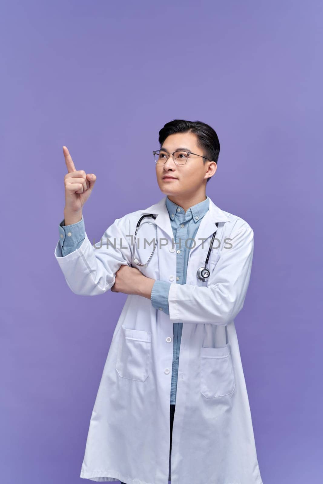Young handsome doctor man smiling cheerfully pointing with forefinger away.