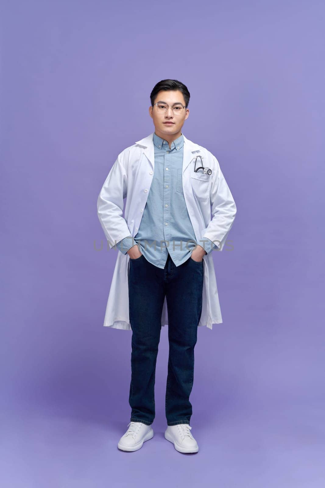 Portrait of male confident doctor over purple background studio, healthcare and Medical technology concept.