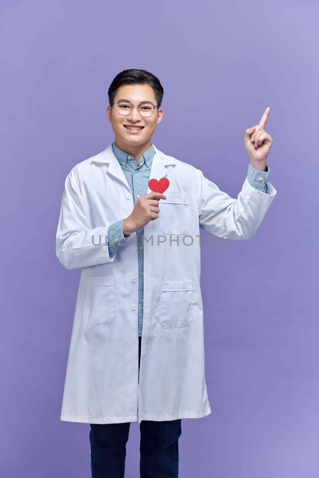 Male doctor man wear white medical gown suit work, show red paper heart mockup point finger