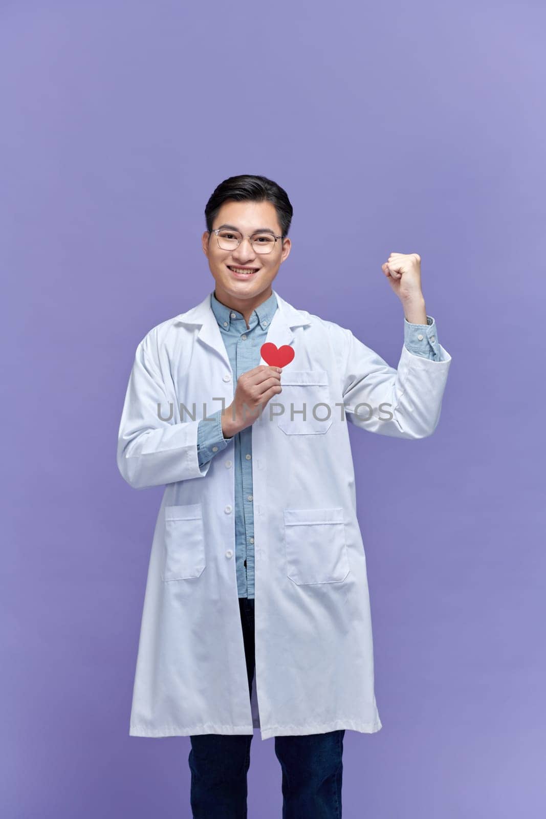 doctor man holding red heart at the clinic screaming proud with raised arm