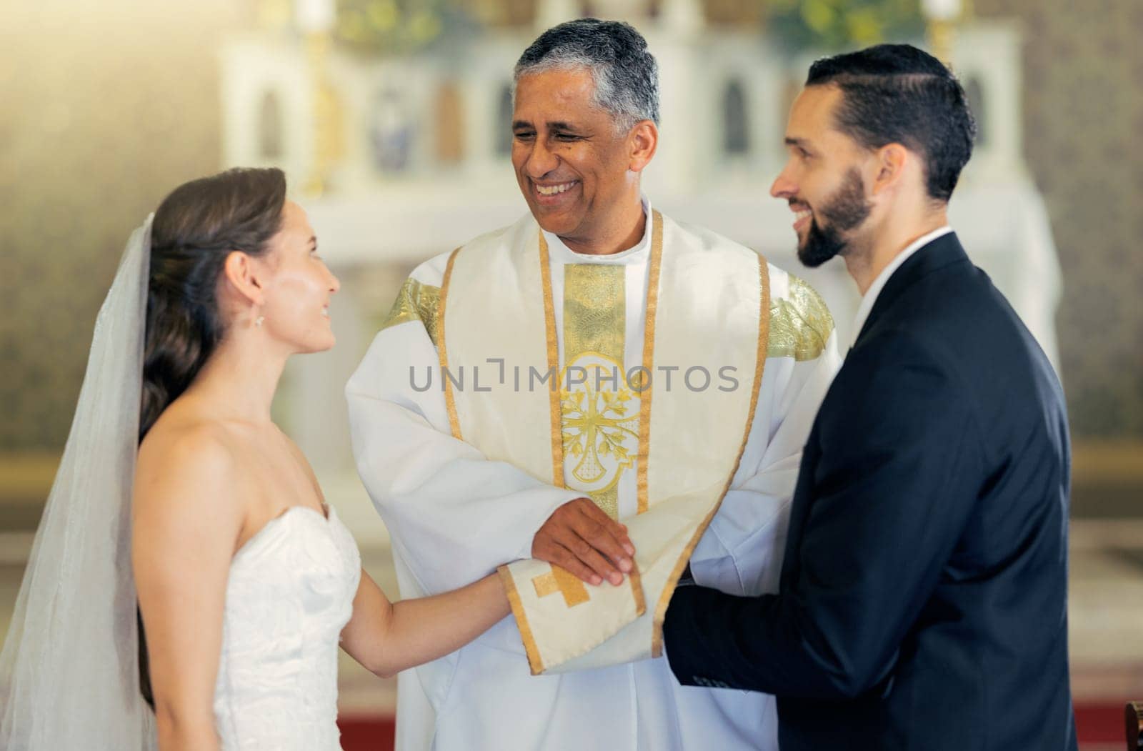 Wedding, priest and couple holding hands in church for a christian marriage oath and faithful commitment. Trust, bride and happy groom with a supportive pastor helping them make a holy love promise by YuriArcurs