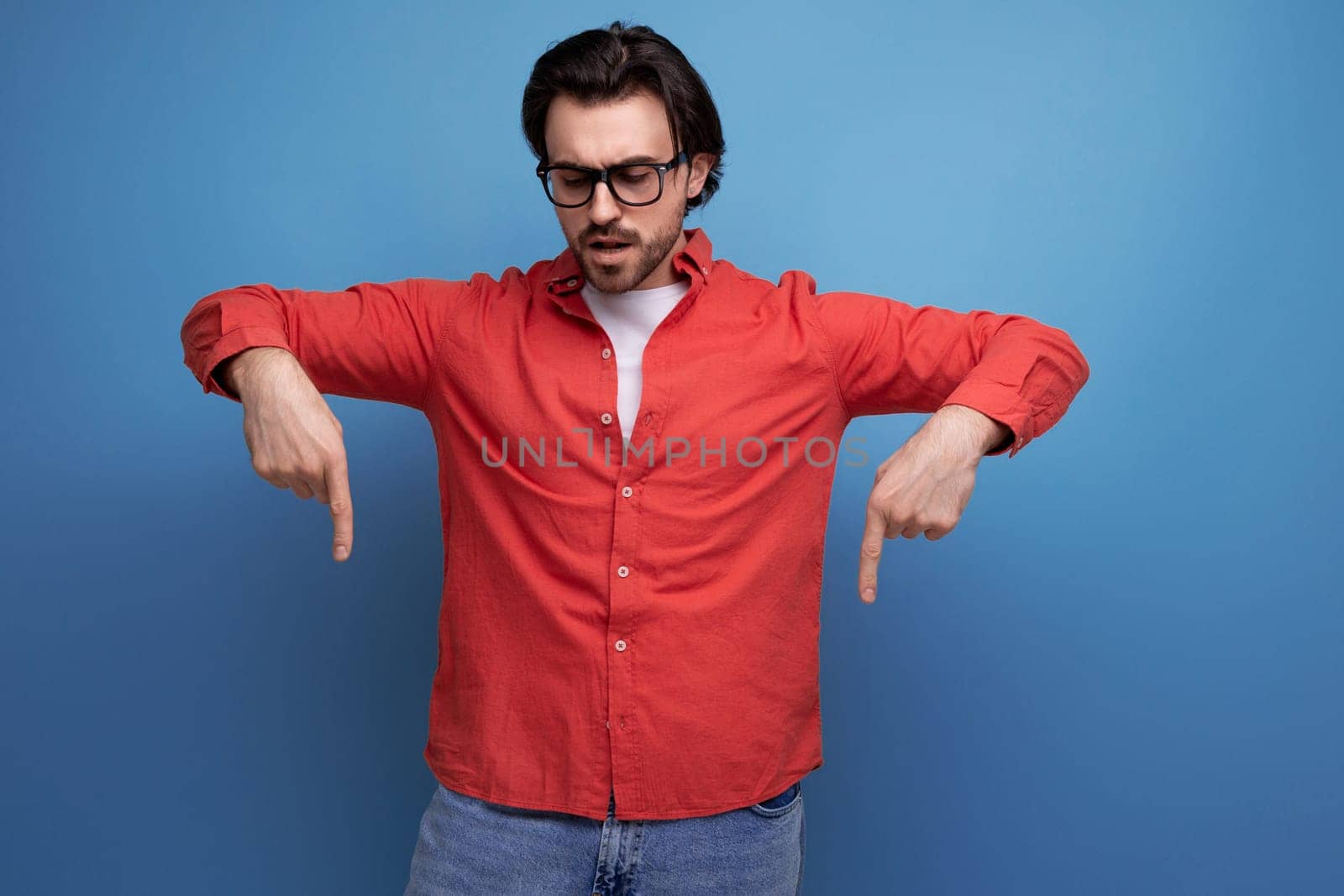 stylish european 35 year old man in casual shirt points finger to the side.