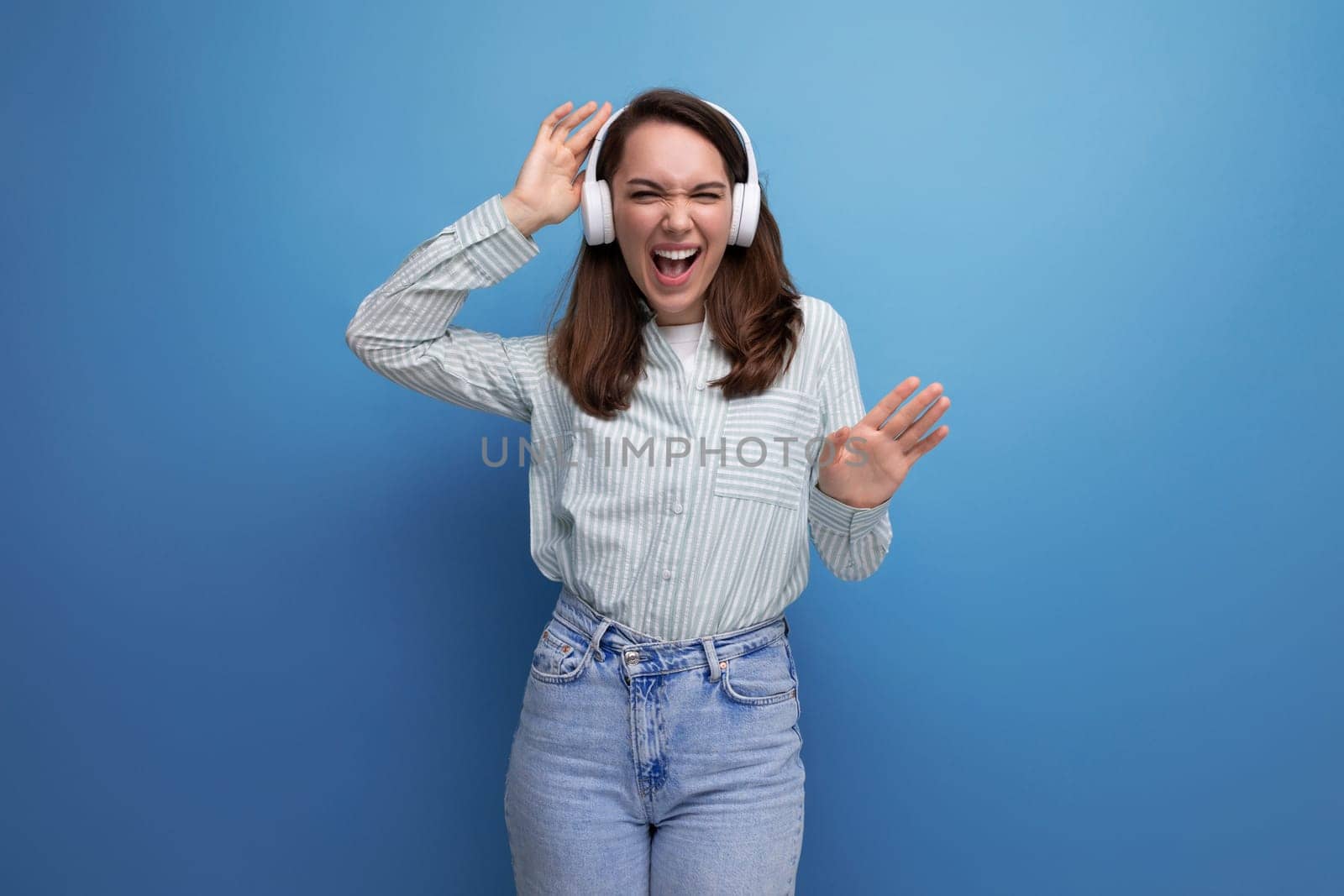 young brown-haired woman rips off to music from wireless headphones by TRMK