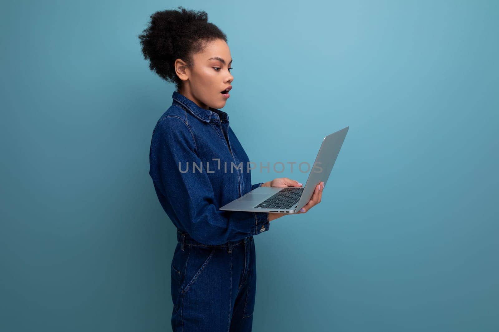 young pretty brunette latin woman with afro ponytail dressed in denim clothes working using laptop.