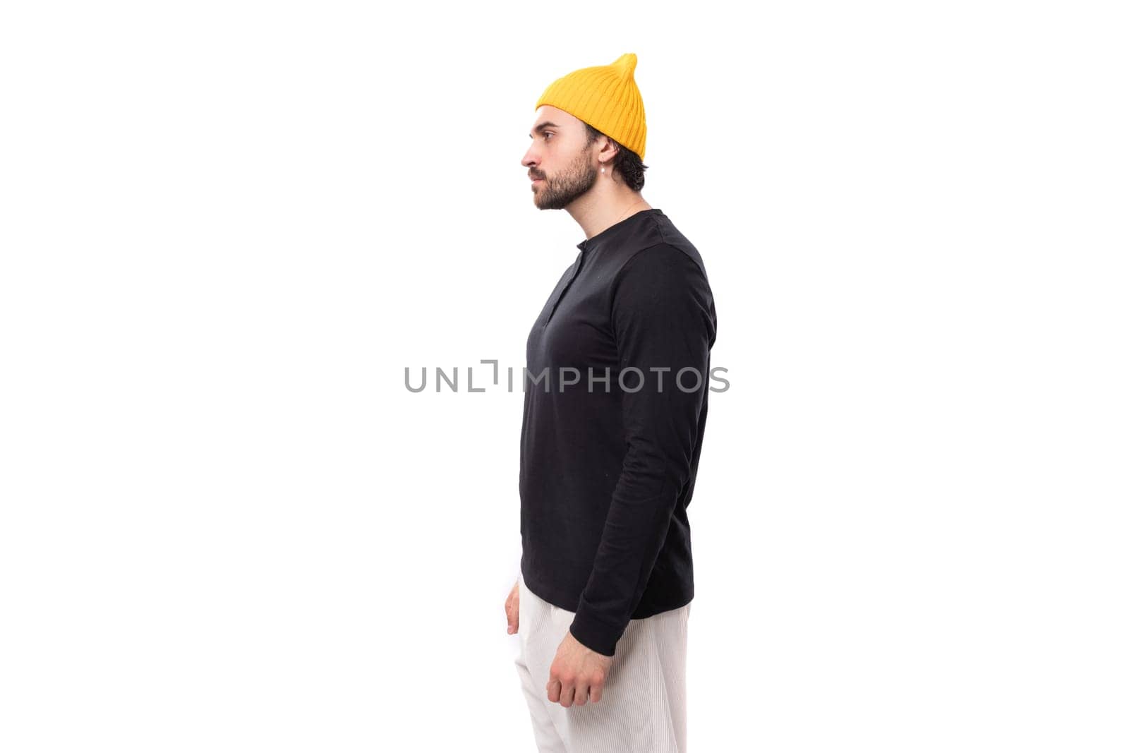 well-groomed authentic brunette male adult in a black sweater stands sideways.