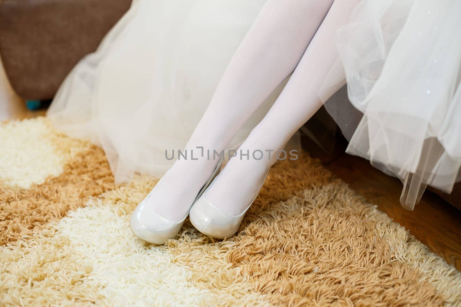 Bride puts white shoes on her legs