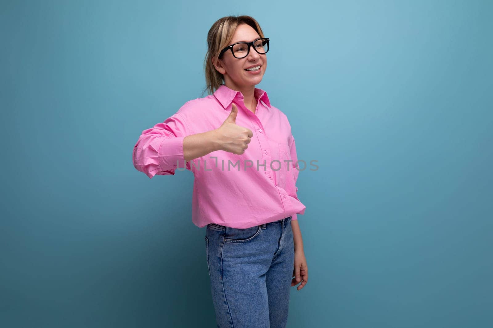 young successful caucasian blond office worker woman dressed in a pink shirt and jeans and glasses with a ponytail hairstyle got a promotion at work and rejoices by TRMK