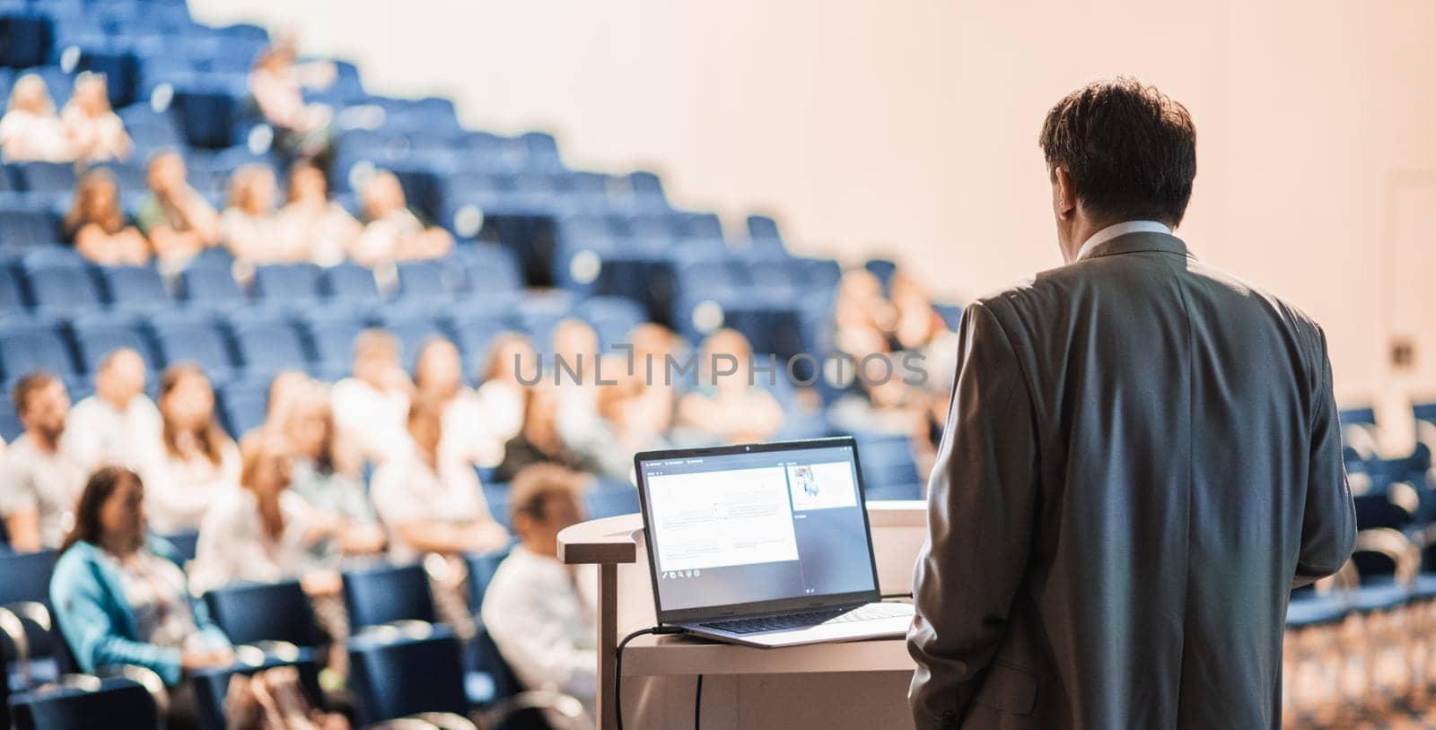 Speaker giving a talk on corporate business conference. Unrecognizable people in audience at conference hall. Business and Entrepreneurship event