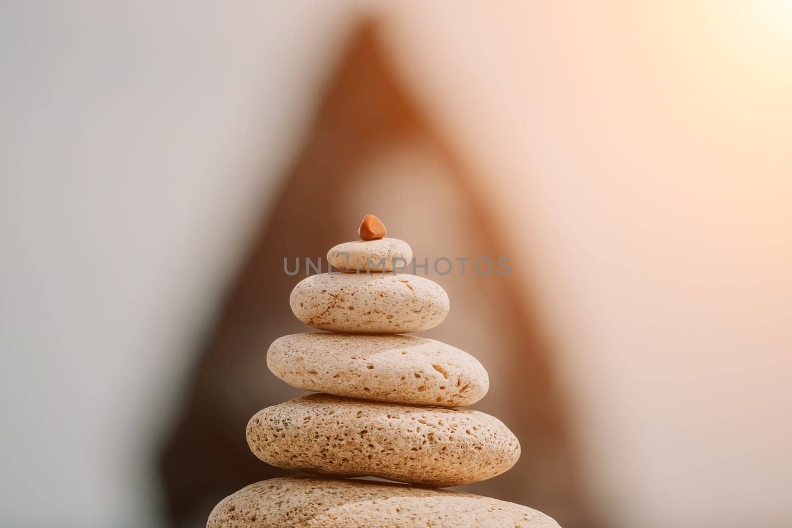 balanced rock pyramid stands tall on sea pebble beach. Selective focus highlights zen stones on the beach, evoking feelings of calm, harmony, and balance. Perfect for meditation or spa concepts. by panophotograph