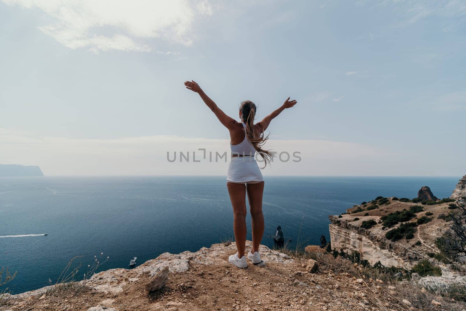 Middle aged well looking woman with black hair doing Pilates with the ring on the yoga mat near the sea on the pebble beach. Female fitness yoga concept. Healthy lifestyle, harmony and meditation.