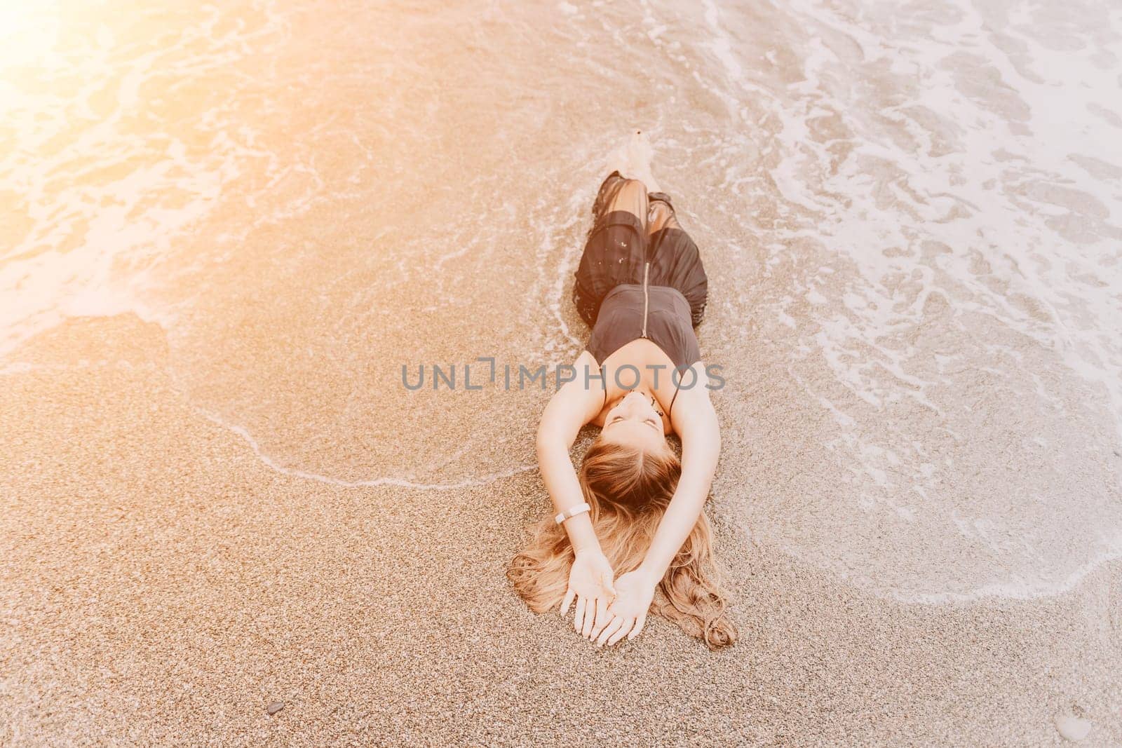 Woman travel sea. Young Happy woman in a long red dress posing on a beach near the sea on background of volcanic rocks, like in Iceland, sharing travel adventure journey