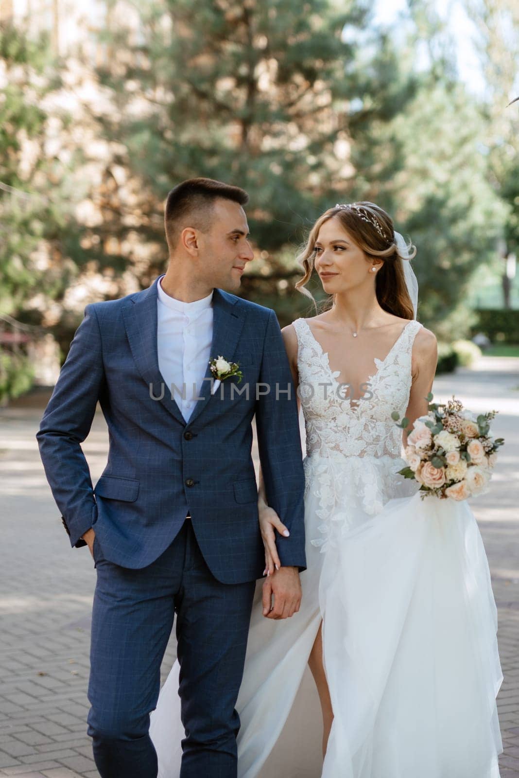 newlyweds walk in the city near old buildings against the backdrop of trees and pines