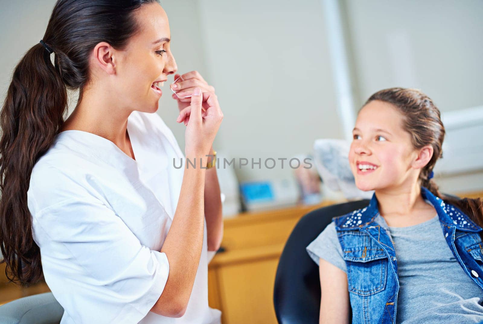 Technique is everything with flossing. a female dentist and child in a dentist office