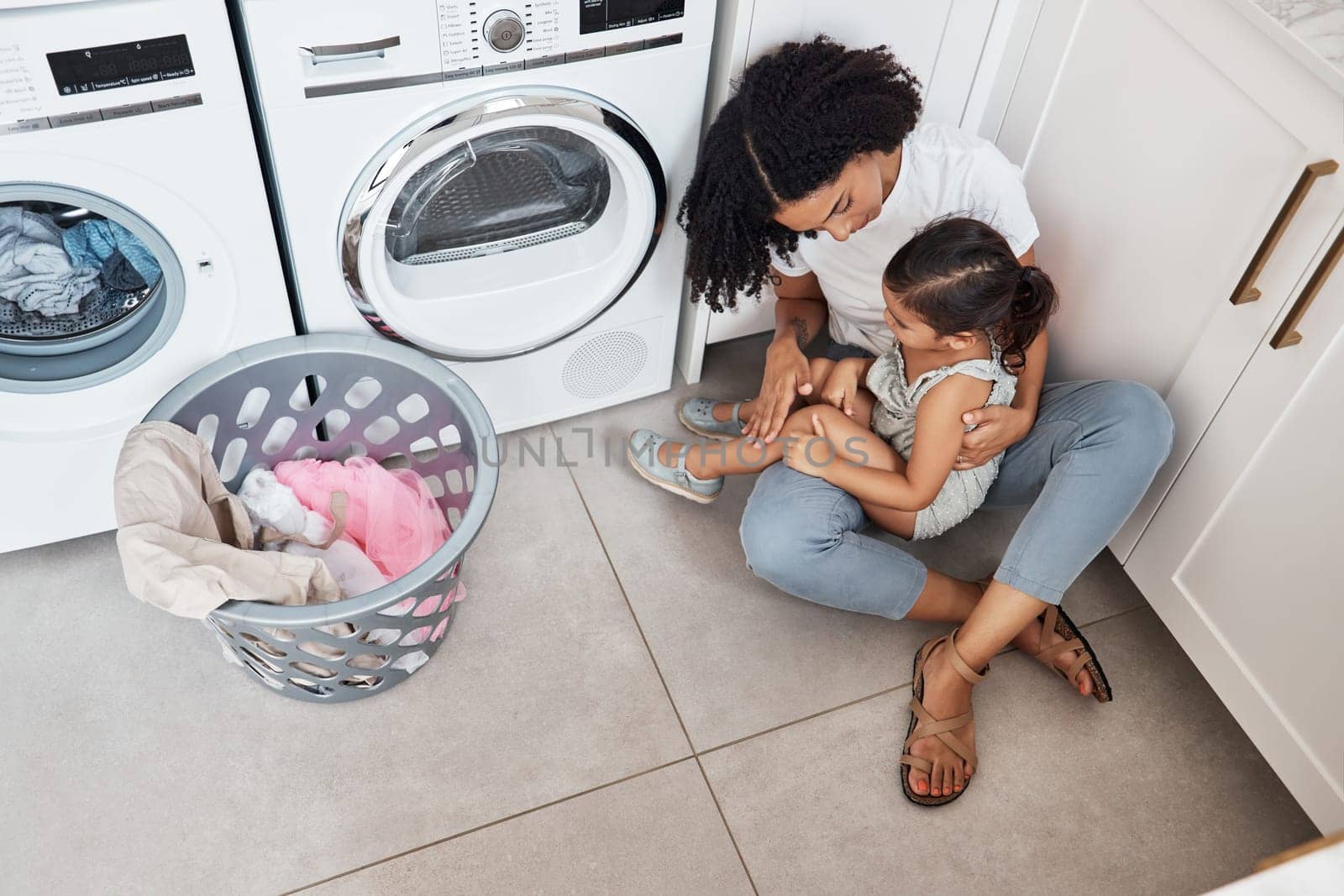 Mom, girl child and hug by washing machine on floor for cleaning, bonding and care in quality time at house. Laundry, mother and daughter with happiness, love and embrace in family home from top view.