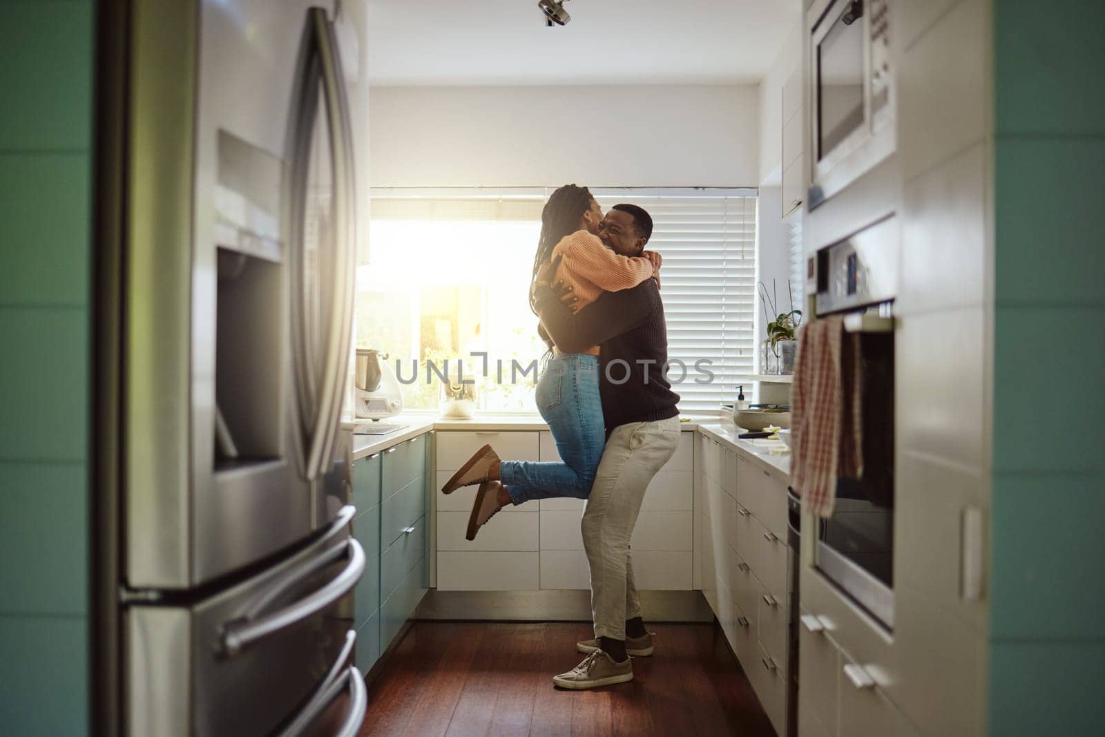 Black couple, happy home and love while together with care and happiness in a marriage with commitment and care. Young man and woman hug while in the kitchen to celebrate their house or apartment.