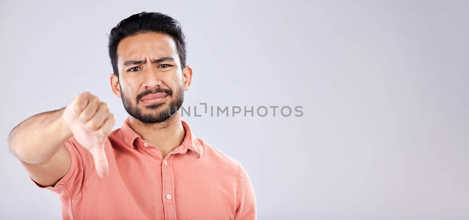 Fail, thumbs down and portrait of Asian man in studio isolated on a gray background mockup. Dislike hand gesture, emoji and face of sad male model with sign for disagreement, rejection or bad review. by YuriArcurs