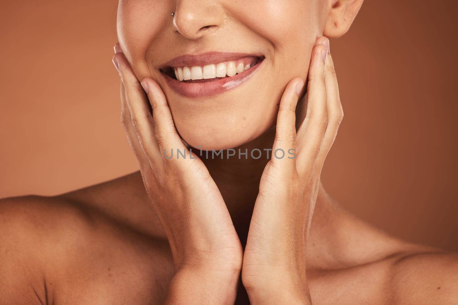 Dental, smile and teeth, oral care and woman on brown studio background. Health, wellness and closeup of female model with hands on face showing her natural looking veneers, healthy mouth and lips by YuriArcurs