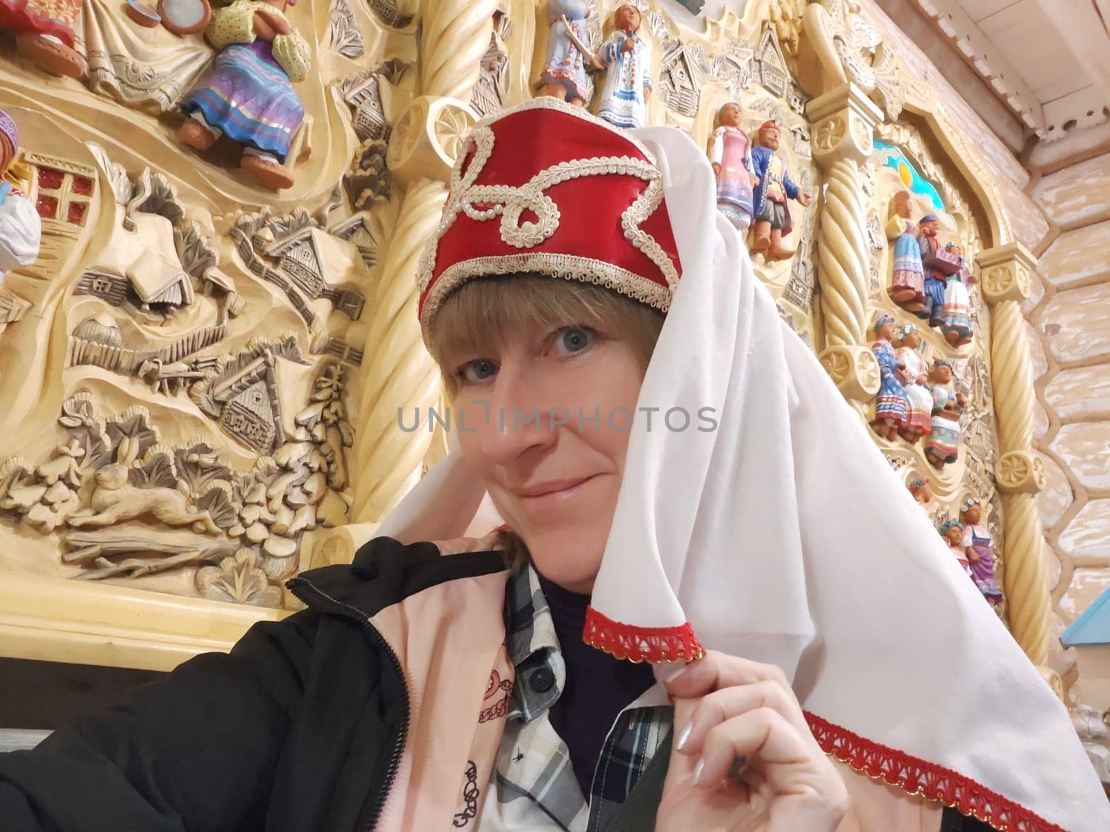 Funny, amusing girl or woman in an old Russian headwear. Female tourist traveling in Russia or Ukraine poses in national costume.