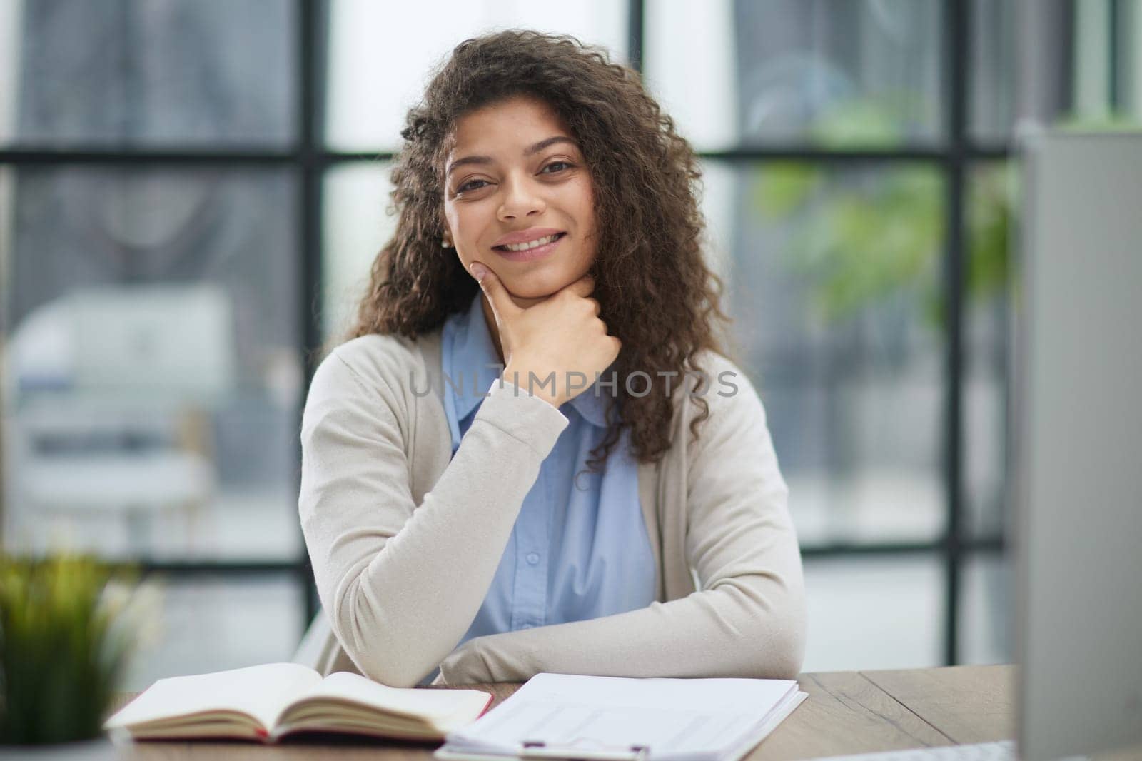 A beautiful young girl stands near the office table by Prosto