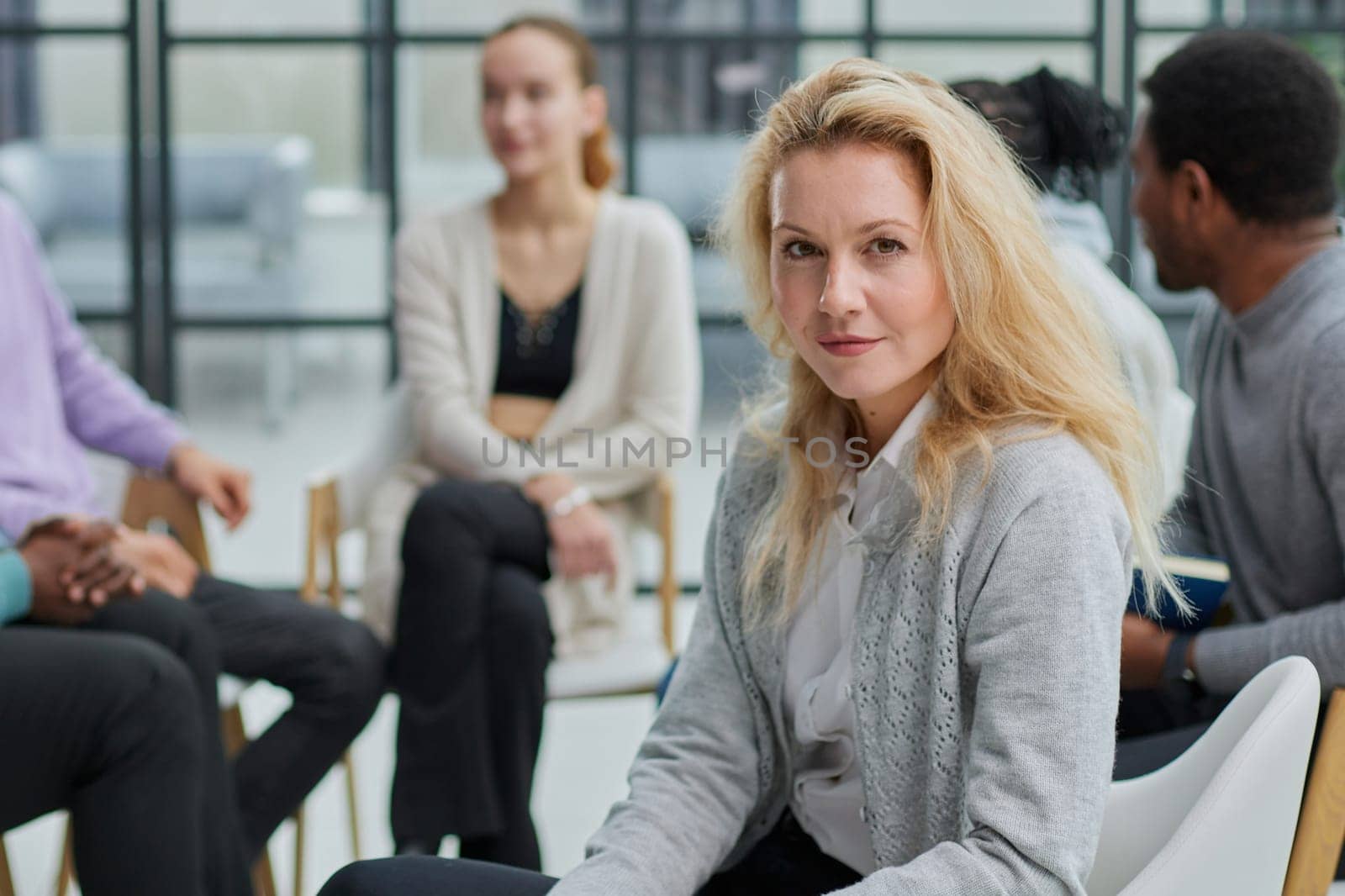 Smiling businesswoman looking at camera at seminar with her colleagues near by by Prosto