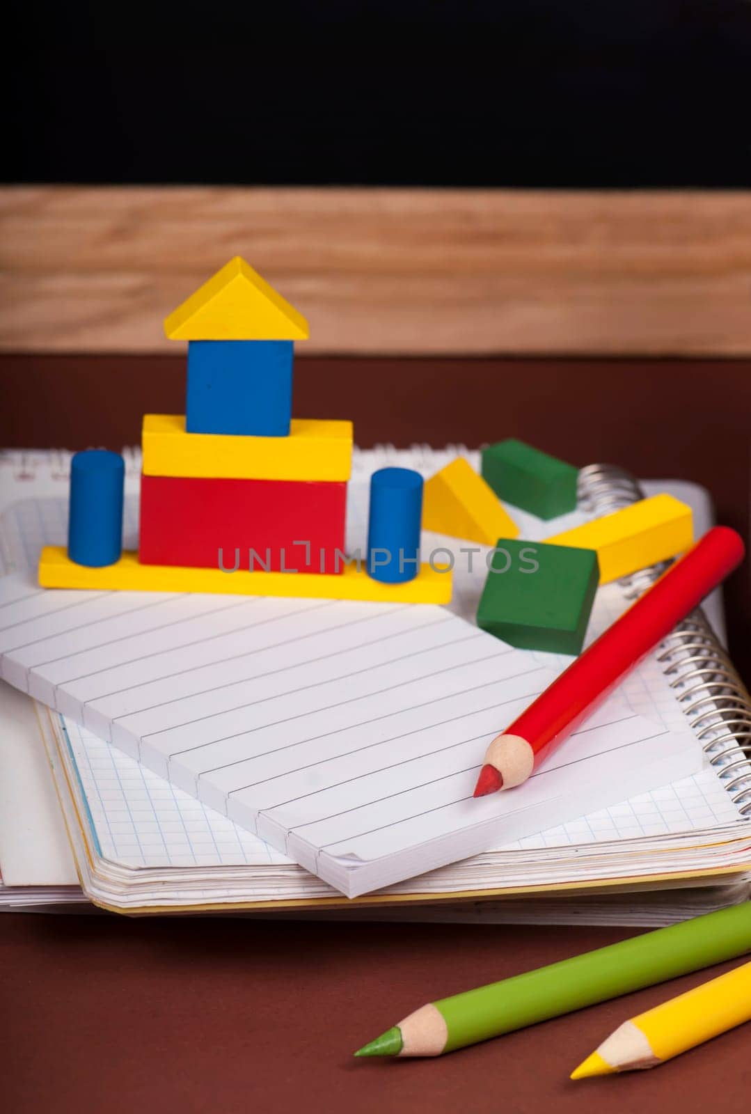 Magnifying glass, scissors, colored paper, textbooks, Apple, cubes, board, pencils, opened empty notebook against a dark background by aprilphoto