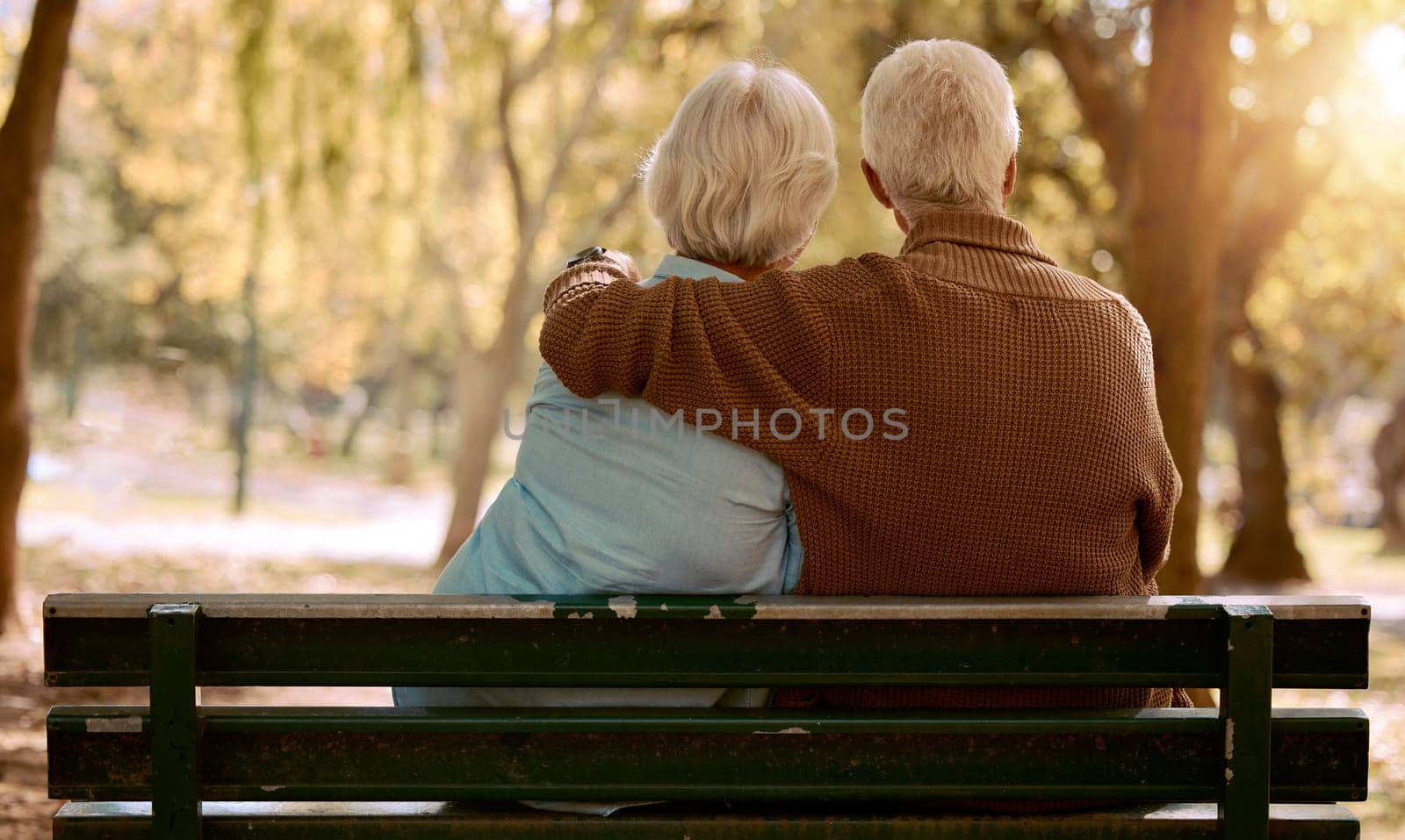 Love, hug and old couple in a park on a bench for a calm, peaceful or romantic summer marriage anniversary date. Nature, romance or back view of old woman and elderly partner in a relaxing embrace by YuriArcurs
