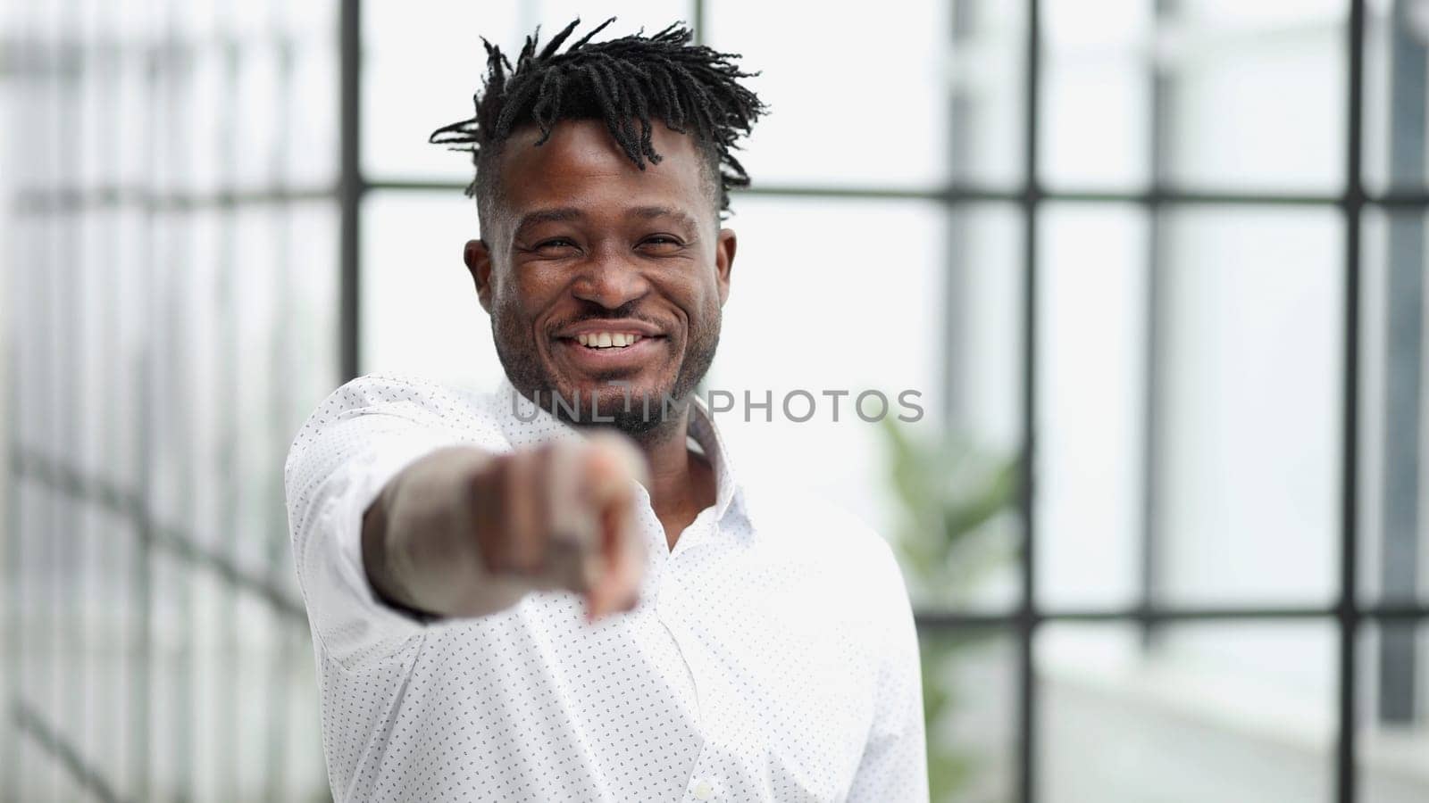 Handsome happy young man in white shirt pointing at camera