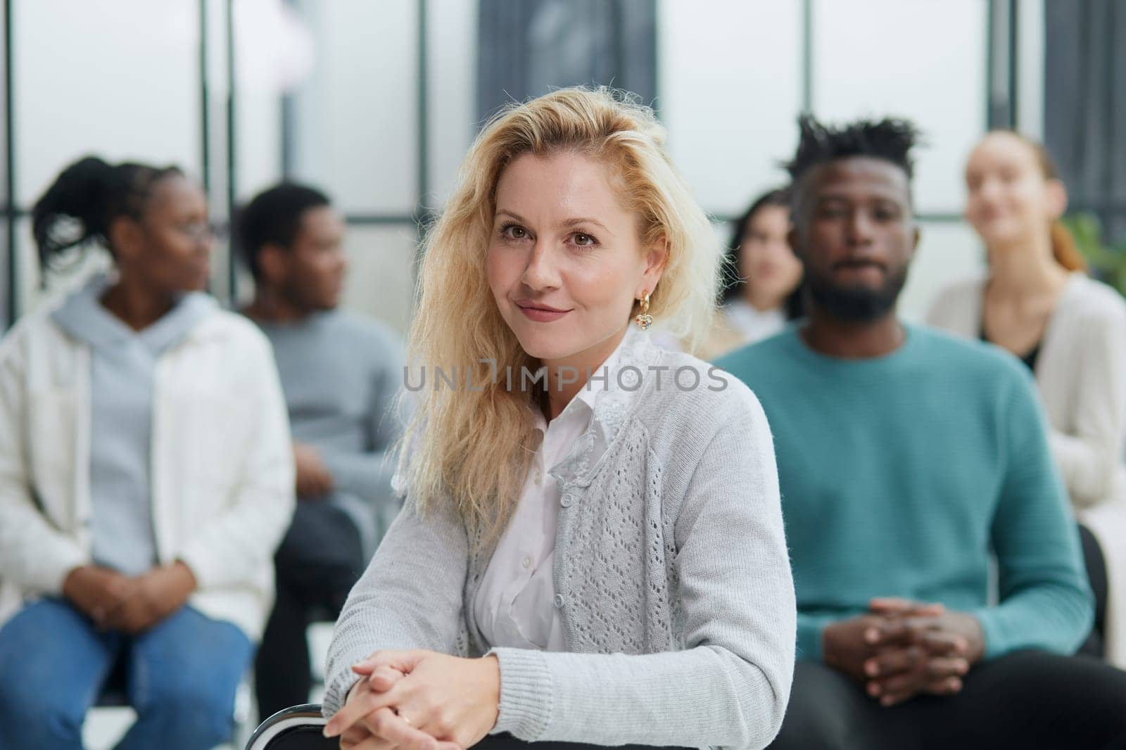 Business woman sitting on a chair with her staff in the background