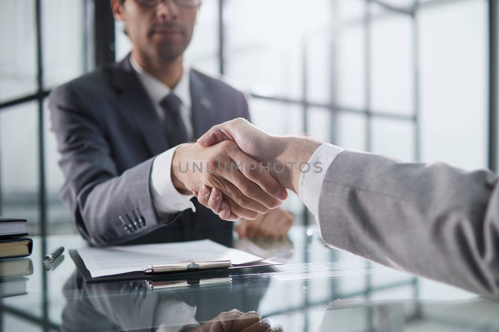 Man shaking hands with partner over office desk