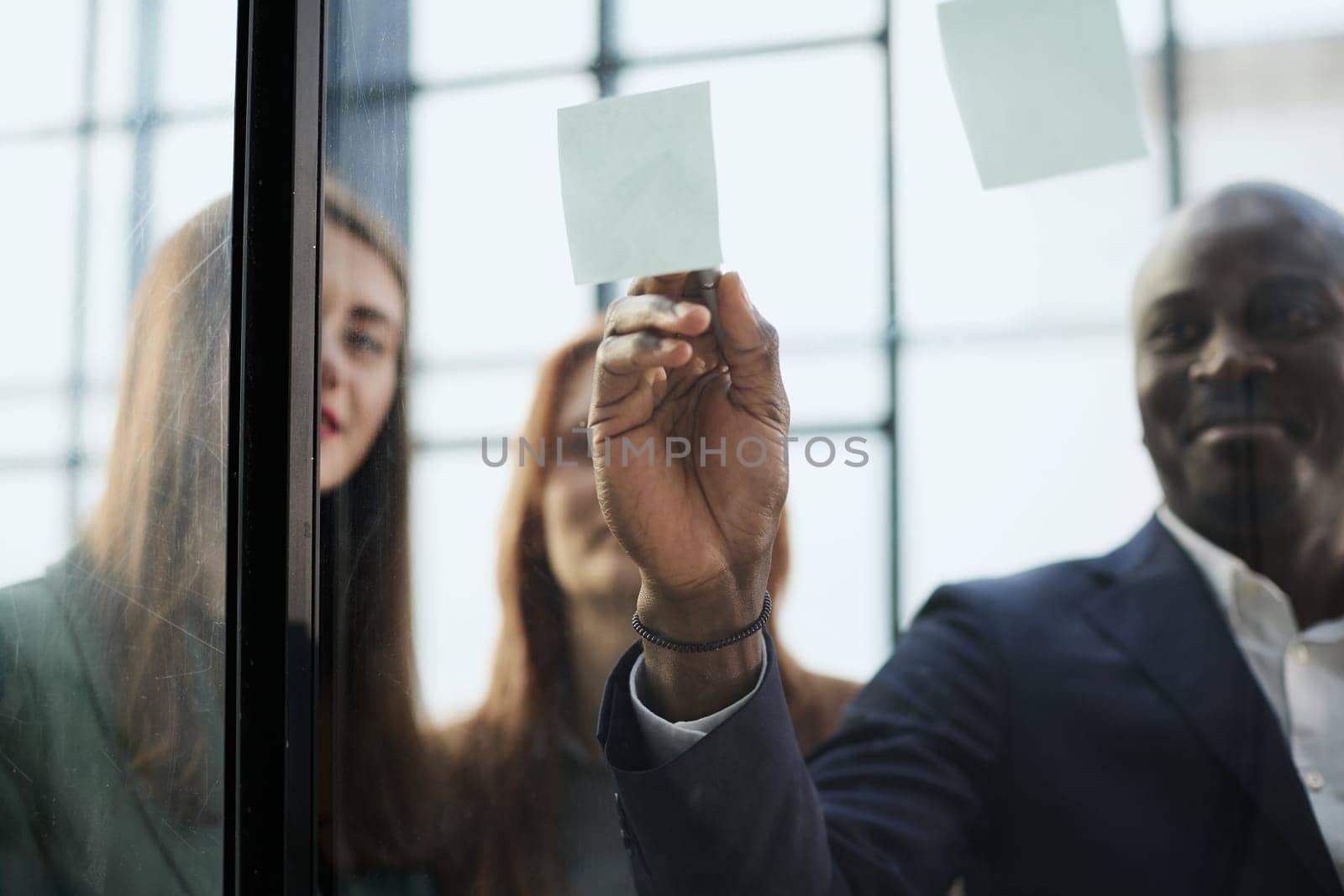 Creative business team looking at sticky notes on glass window