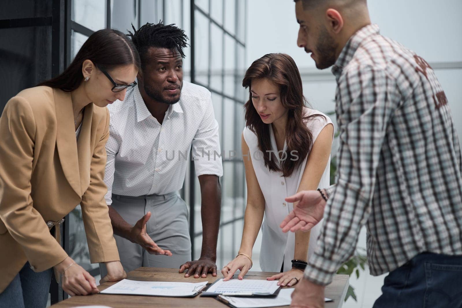 Group of young business people working together while standing in creative office