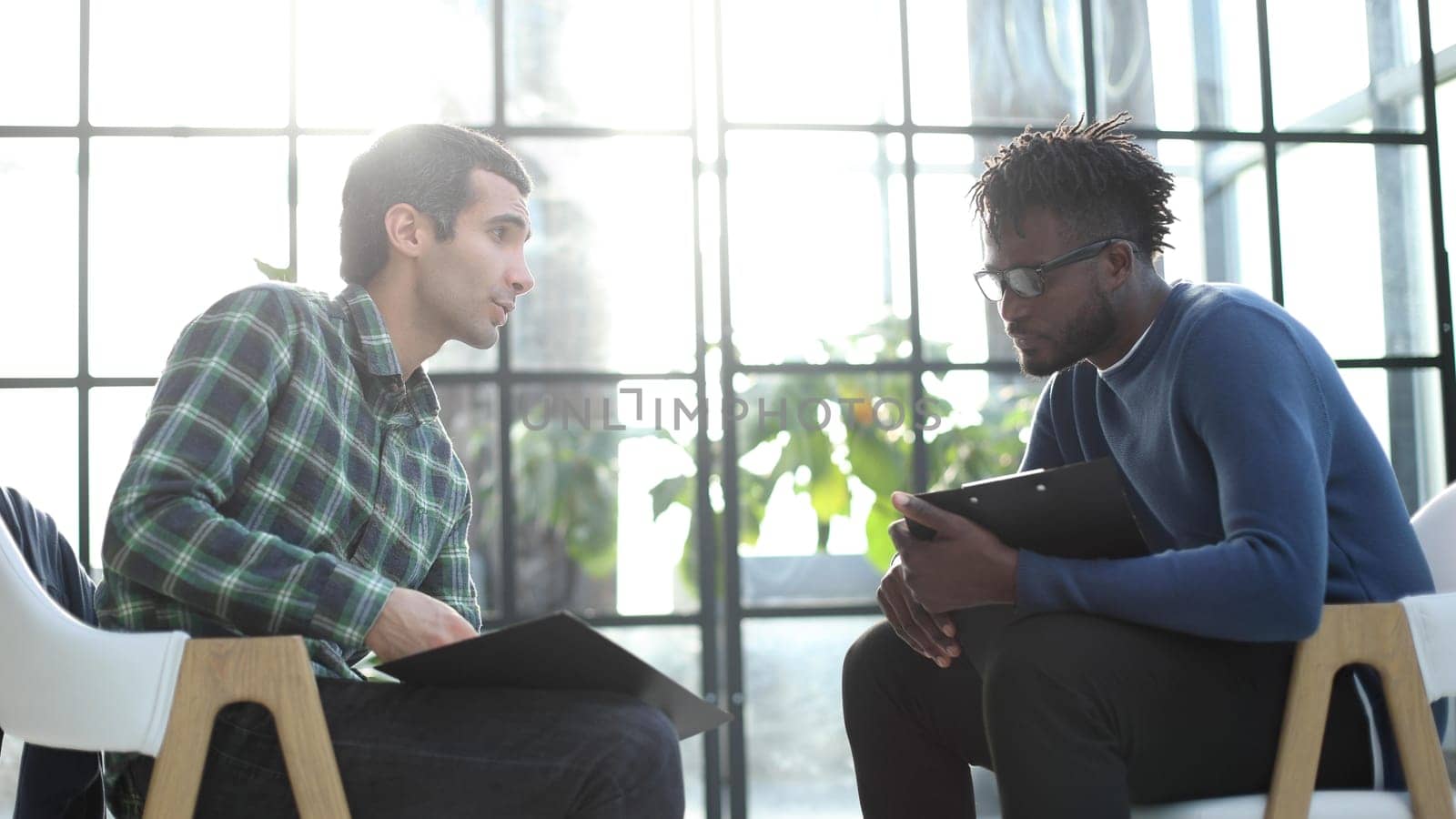 Thoughtful business man in formalwear holding paper while sitting at chair fills out a resume questionnaire in office
