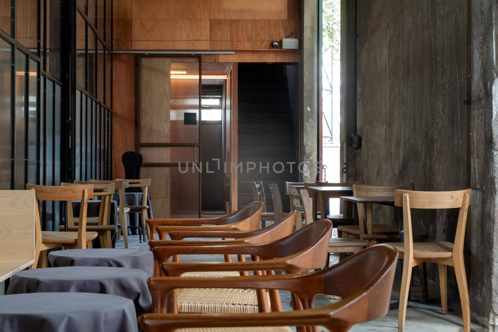 The View of an Empty Cafe's Terrace are decorated with Wooden Tables and Wooden Chairs. Exterior of the Cozy Cafe in the Loft Style, Space for text, Selective focus.