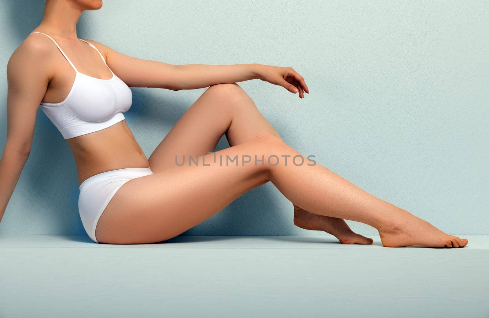 Beautiful slim body of young woman in white underwear on grey background by Nobilior