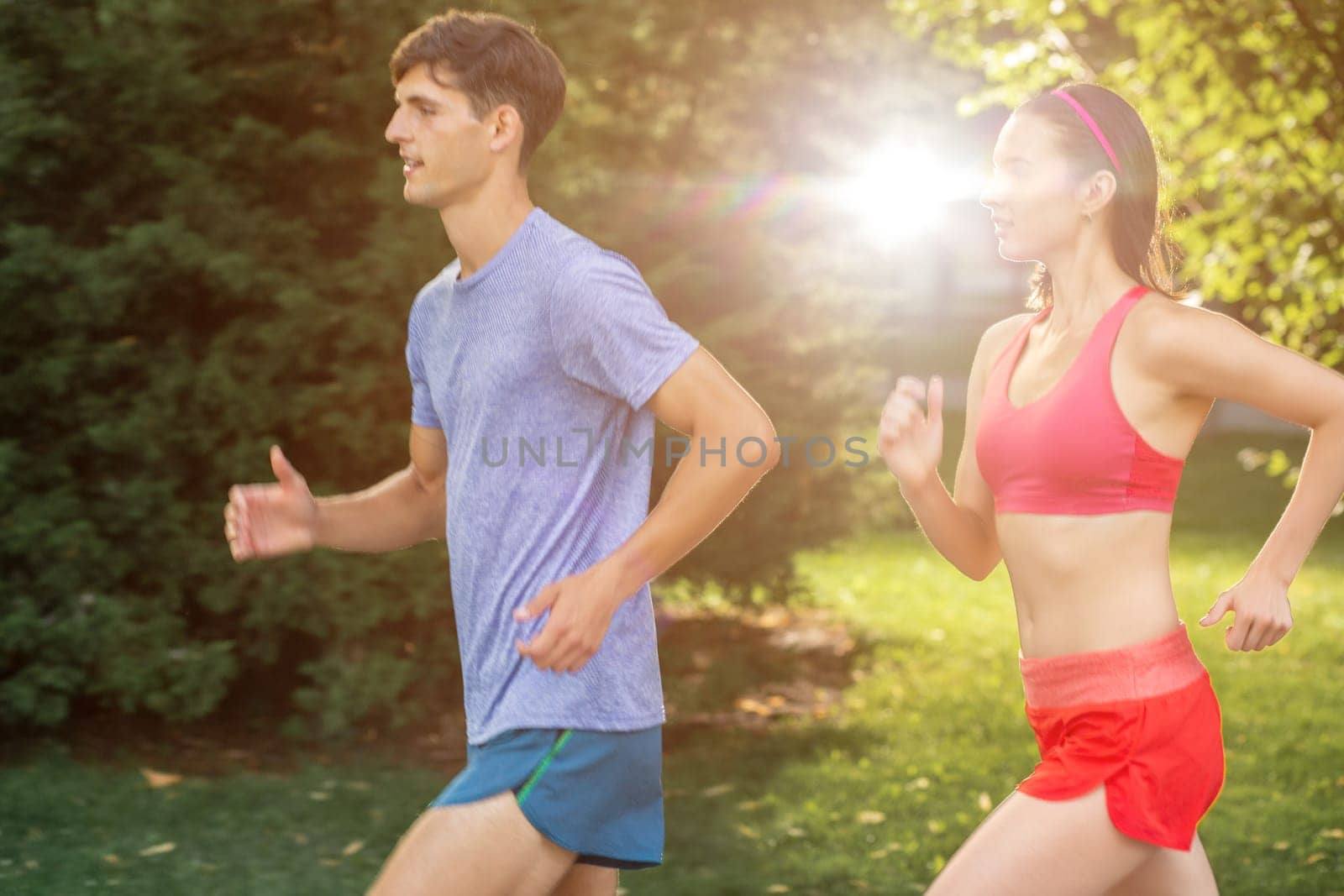 Portrait of cheerful caucasian couple running outdoors. Sun flare.